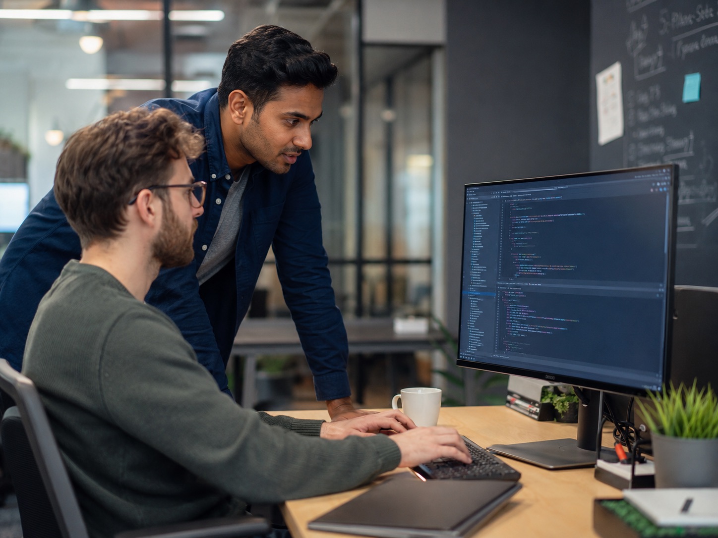 Two engineers reviewing code together on a workstation